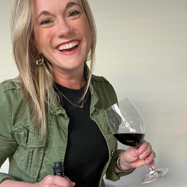 Kristy Wentz holds bottle of wine and glass half full of red wine