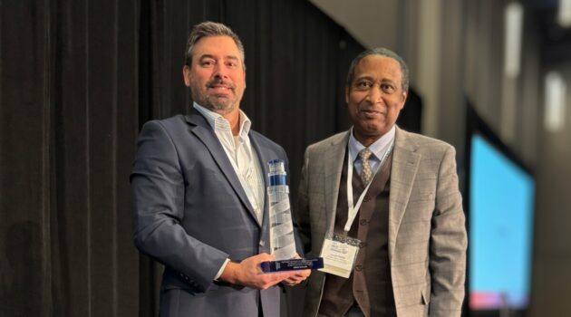 Joe Latulippe (left) holds Beacon Award trophy next to rep from NWCCU.