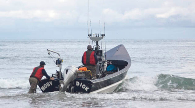 Fisherman pushes out a dory boat into the ocean. Boat name is "Moby Dick". Photo by Ty Marshall.