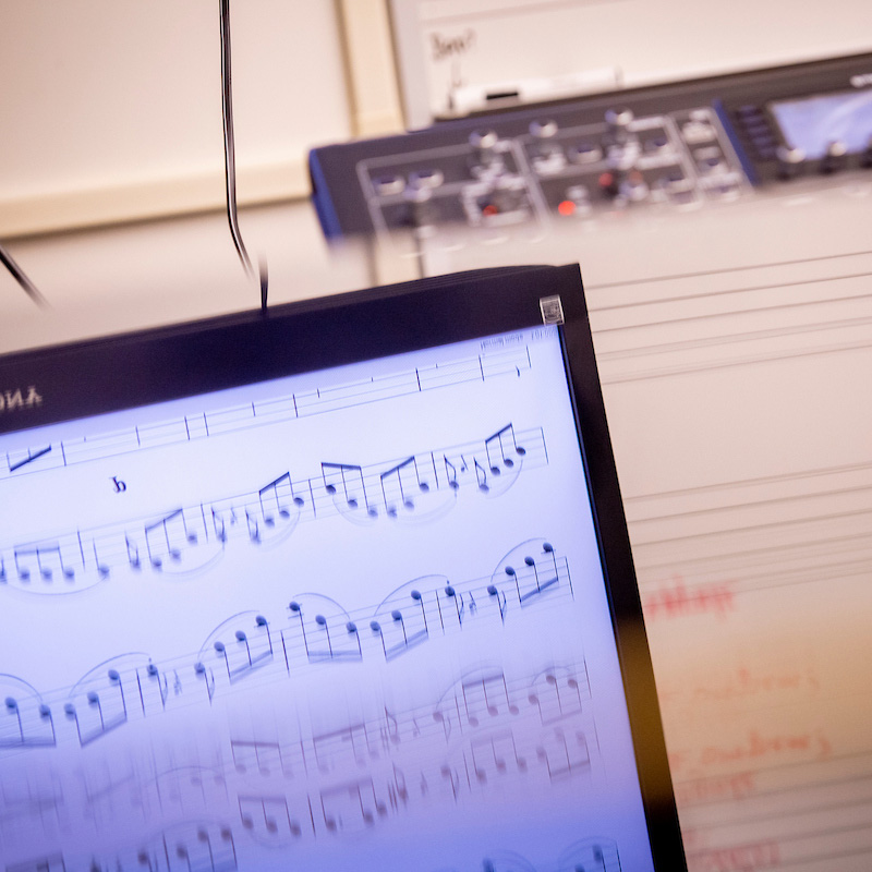 Student composition work on a digital screen on the left and paper on the right