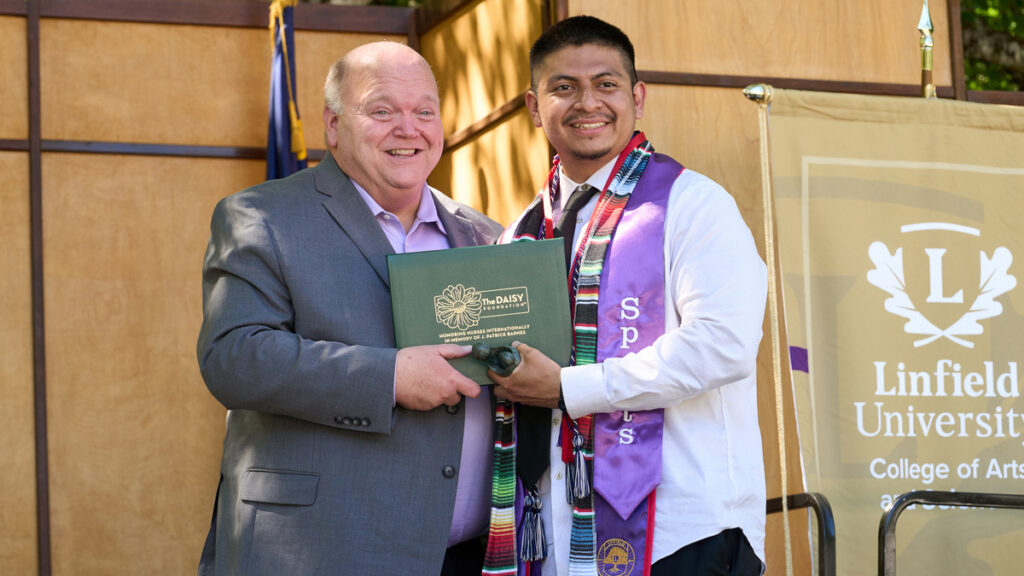 Dean Paul Smith stands next to Steven Duran holding the green DAISY nursing award.