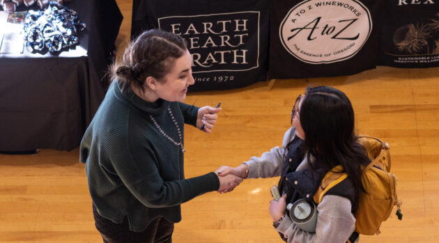 student shakes hand with employer at job fair