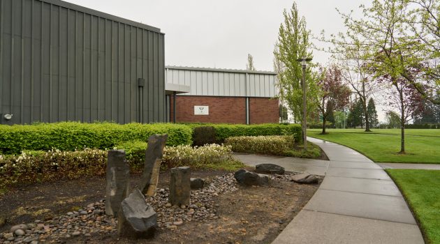 The outside of Loveridge Hall, with a path winding around the building and decorative rocks in teh foreground.