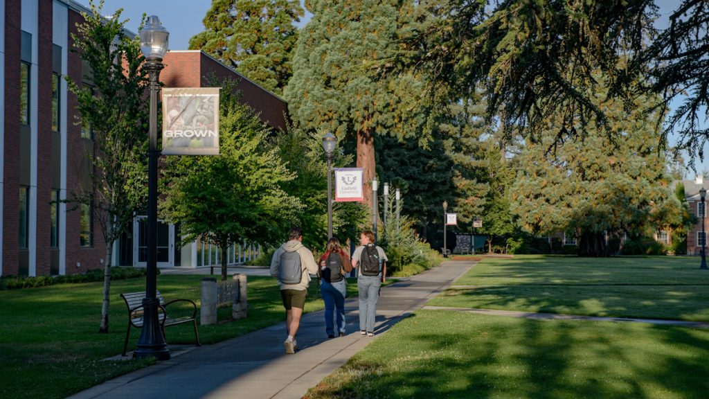 Three students walk across the Linfield University McMinnville Campus on the first day of fall semester.