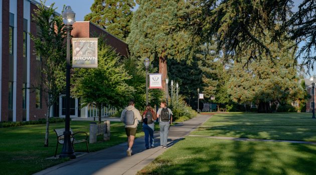 Three students walk across the Linfield University McMinnville Campus on the first day of fall semester.