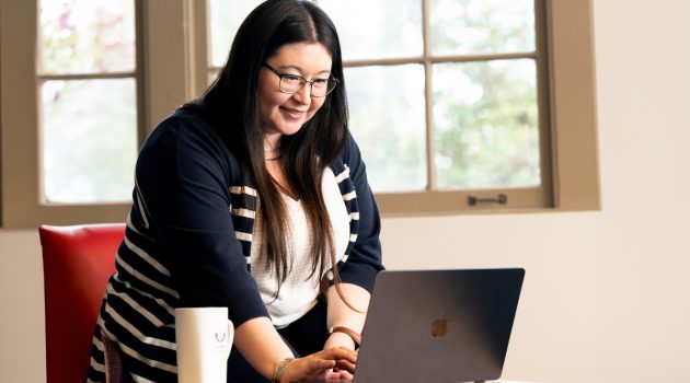 Student Azia Salbego sits behind a laptop with a cup of coffee.